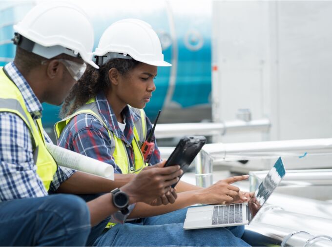 Engineers working together at a worksite looking at laptop.